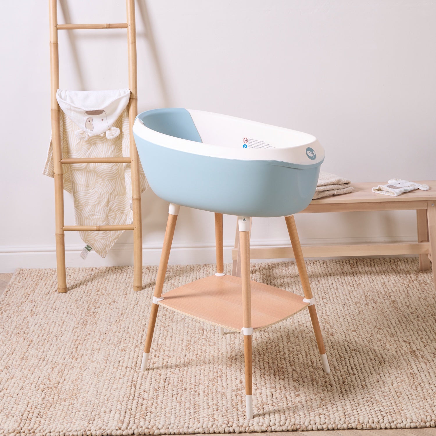Nati Baby Bath in ocean on wooden stand with storage shelf, styled in a calming nursery-inspired bathroom setting.