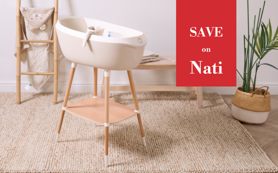 A cream-colored Nati bath with light wood legs and a complementary wooden shelf, styled in a nursery setting on a woven rug with a red promotional text overlay that reads 'SAVE on Nati'.