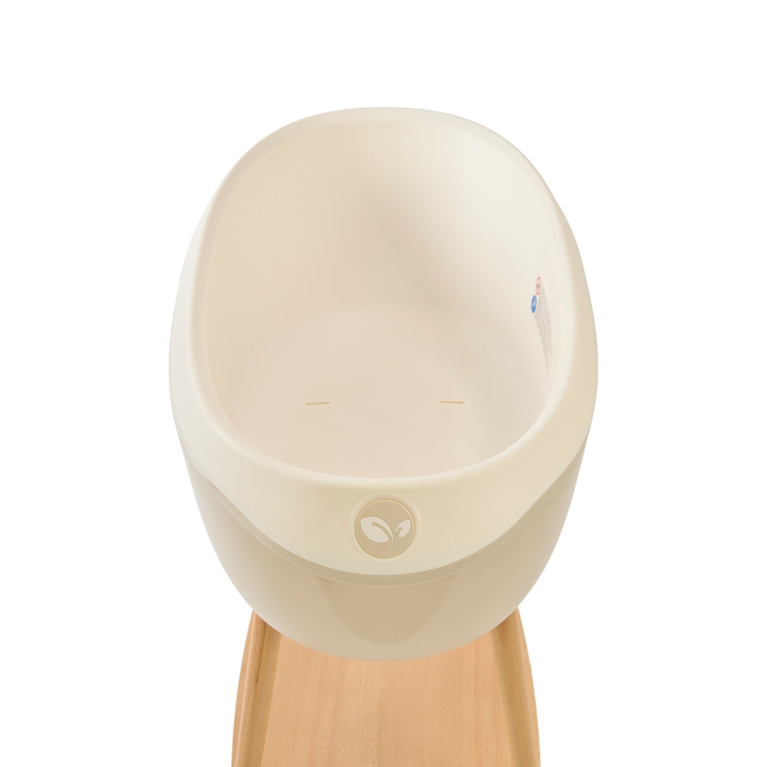 Inside view of the Nati Baby Bath in Dune, placed on its wooden stand against a clean white background. 
