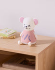 Mouse night light in white with a pink dress on a wooden nightstand with books below.