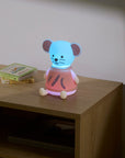 Children's night light shaped like a mouse on a wooden nightstand with a book in the background.