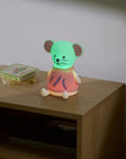 Children's night light shaped like a mouse on a wooden nightstand with a book in the background.