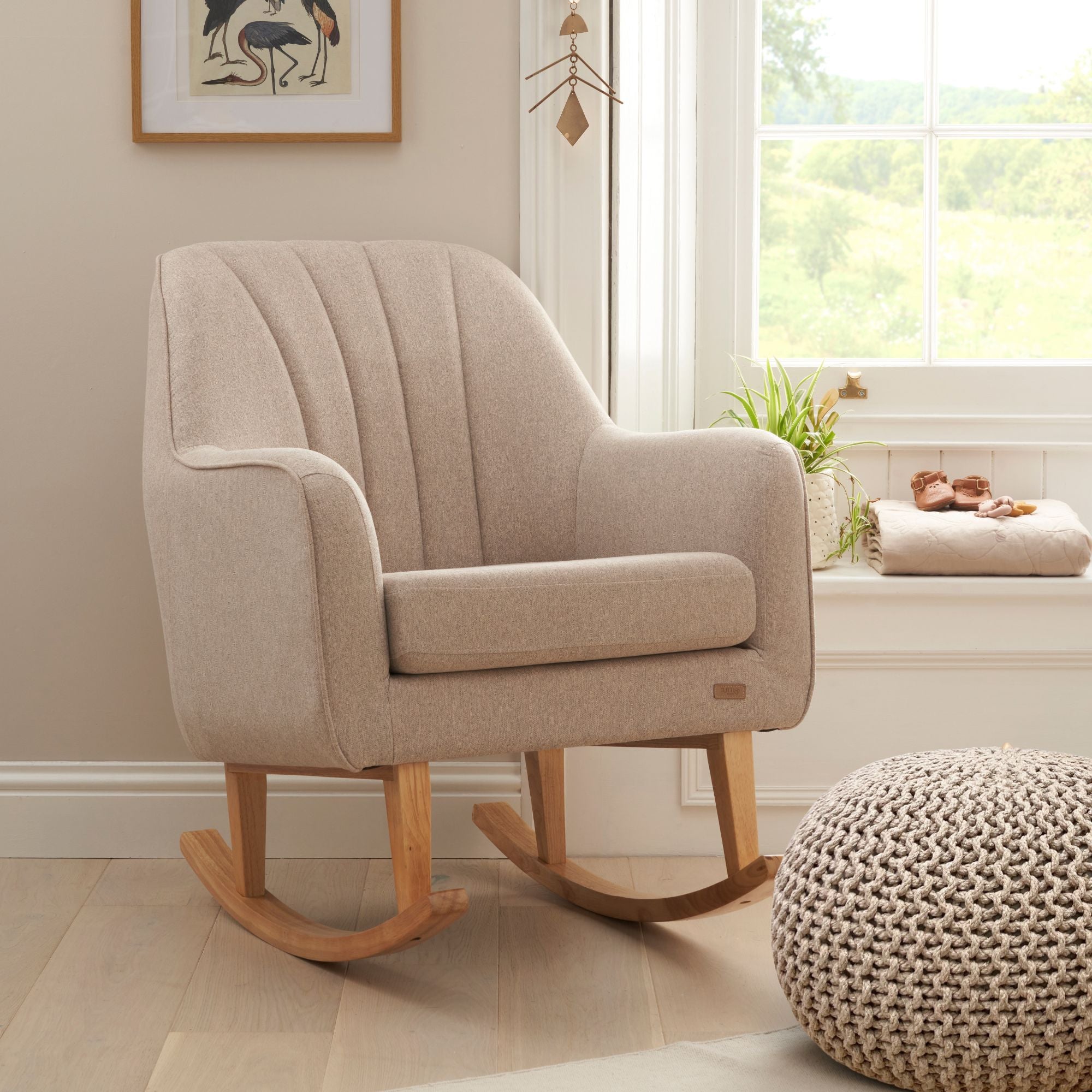 Noah rocking chair in beige in a room with a window and decorative items.