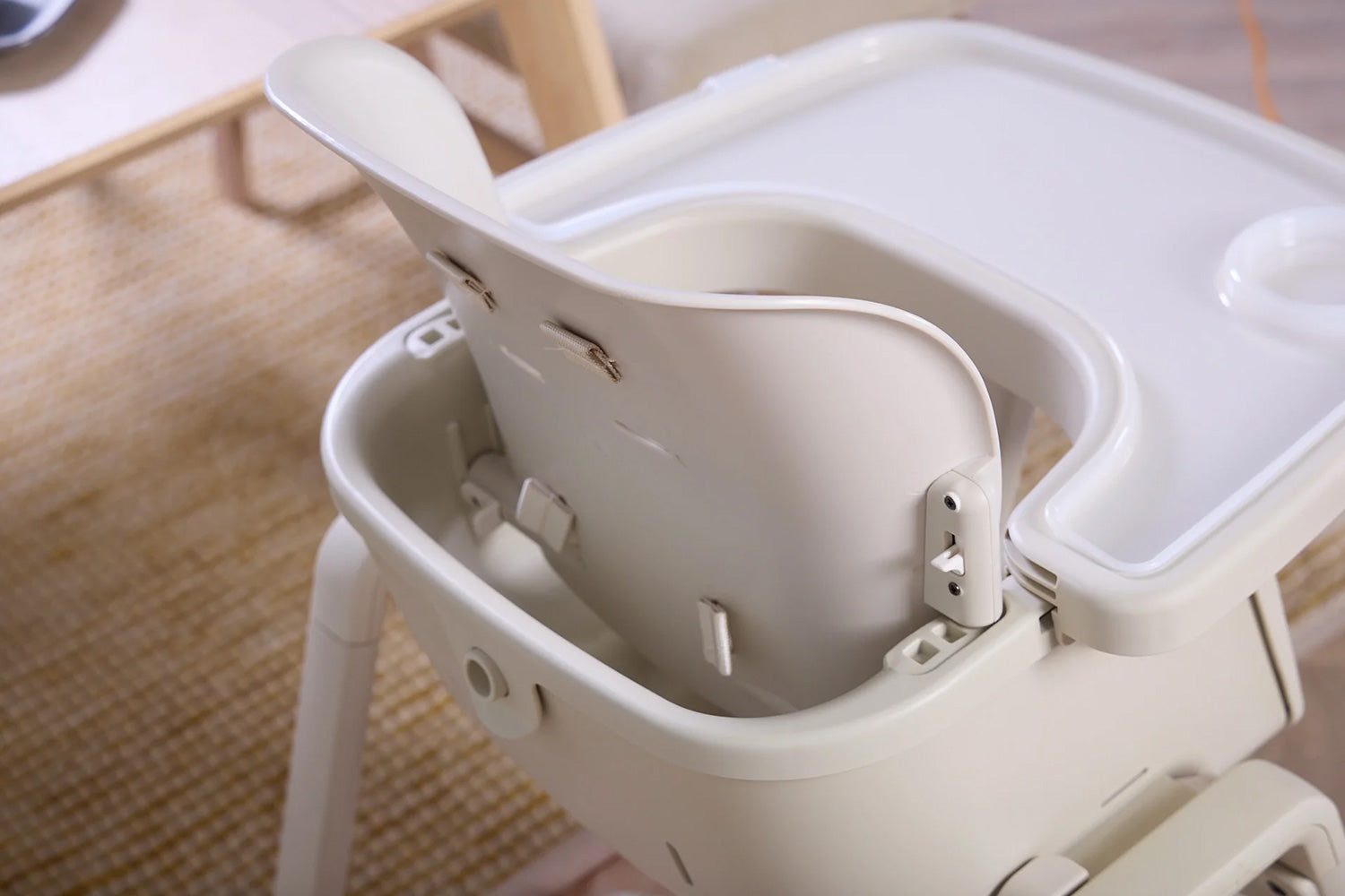 Close-up of the Nova beige highchair with a white tray on a wooden floor.