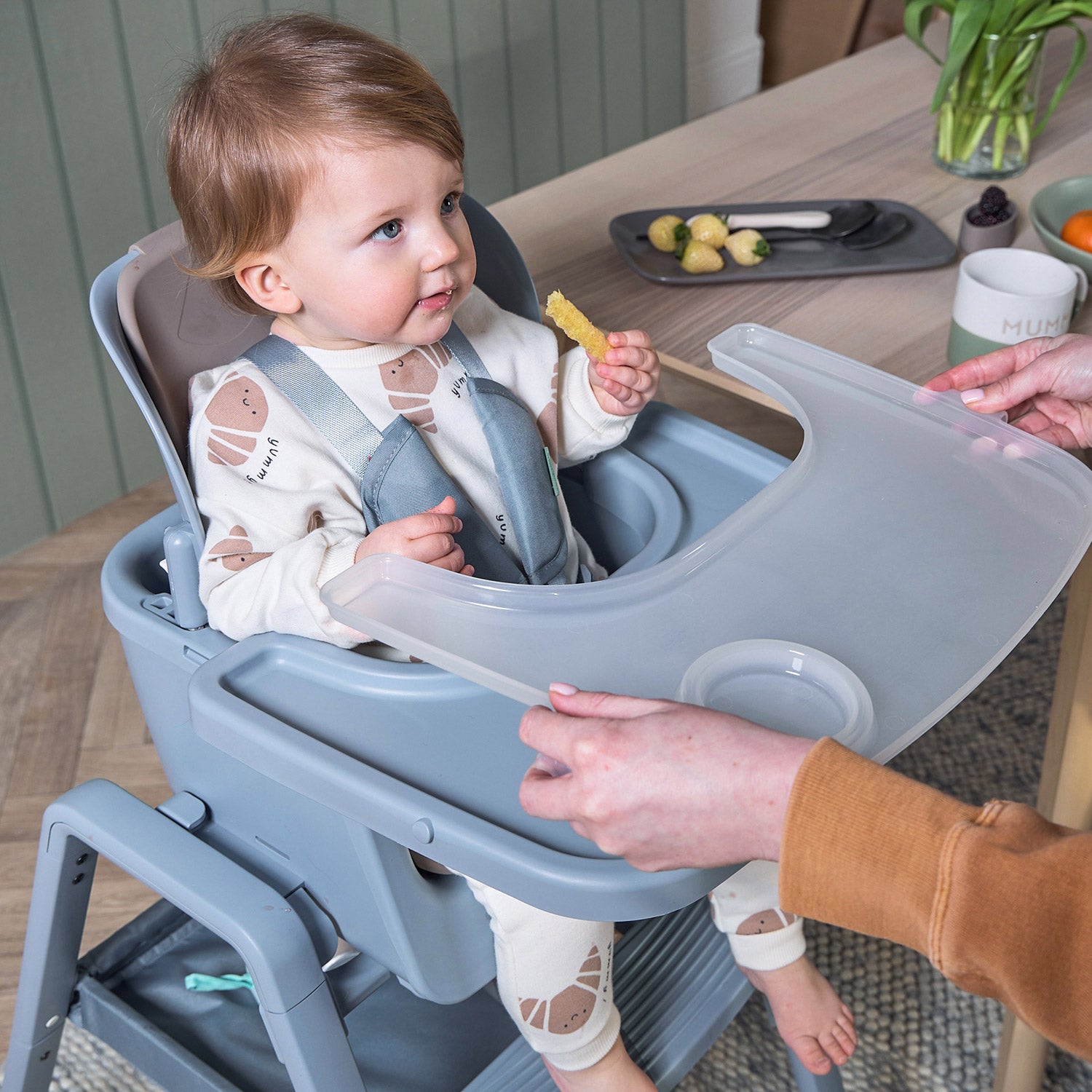 parent easily removes tray of the nova maison in coast as the toddler sits contently eating.