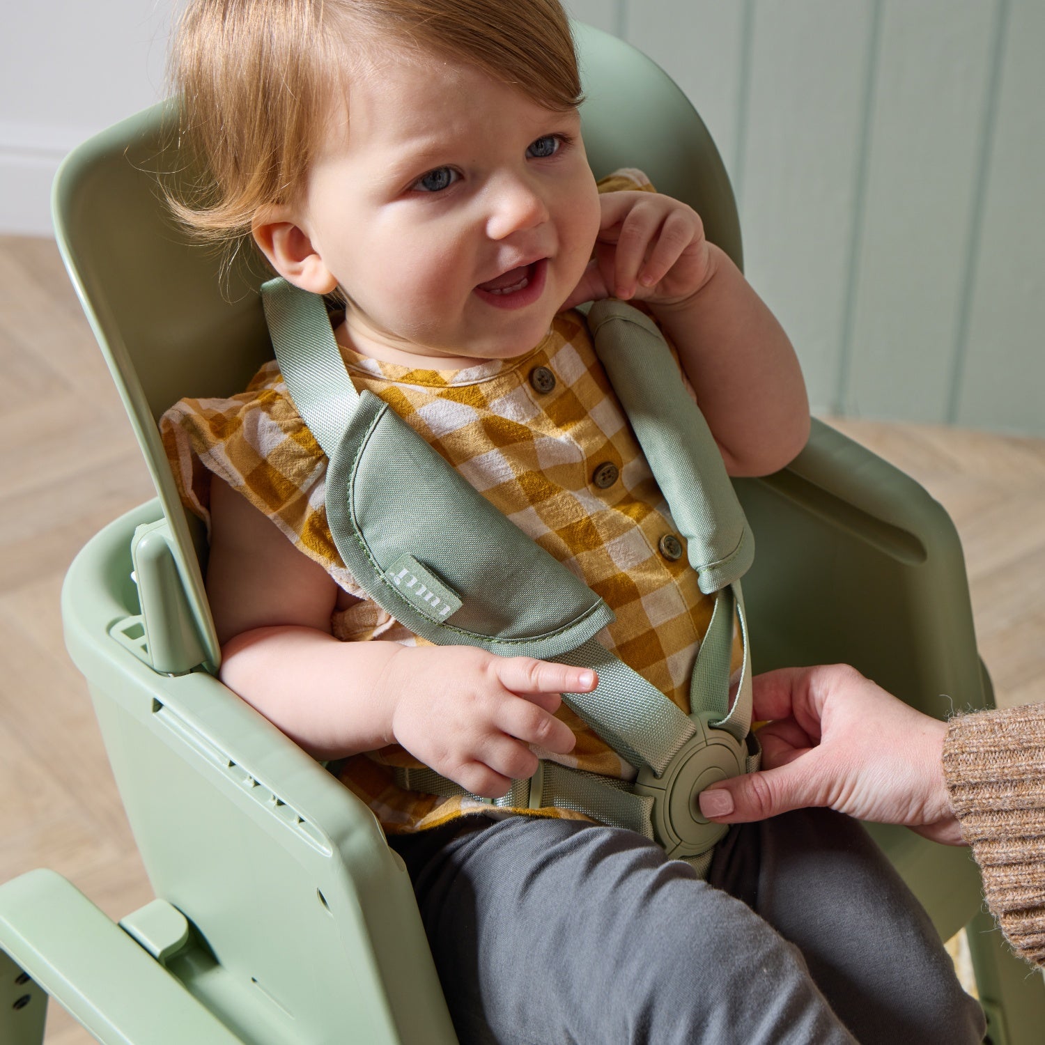 Close-up of a child seated in the nova maison 7 in highchair in matcha, highlighting padded harness and supportive seating position.