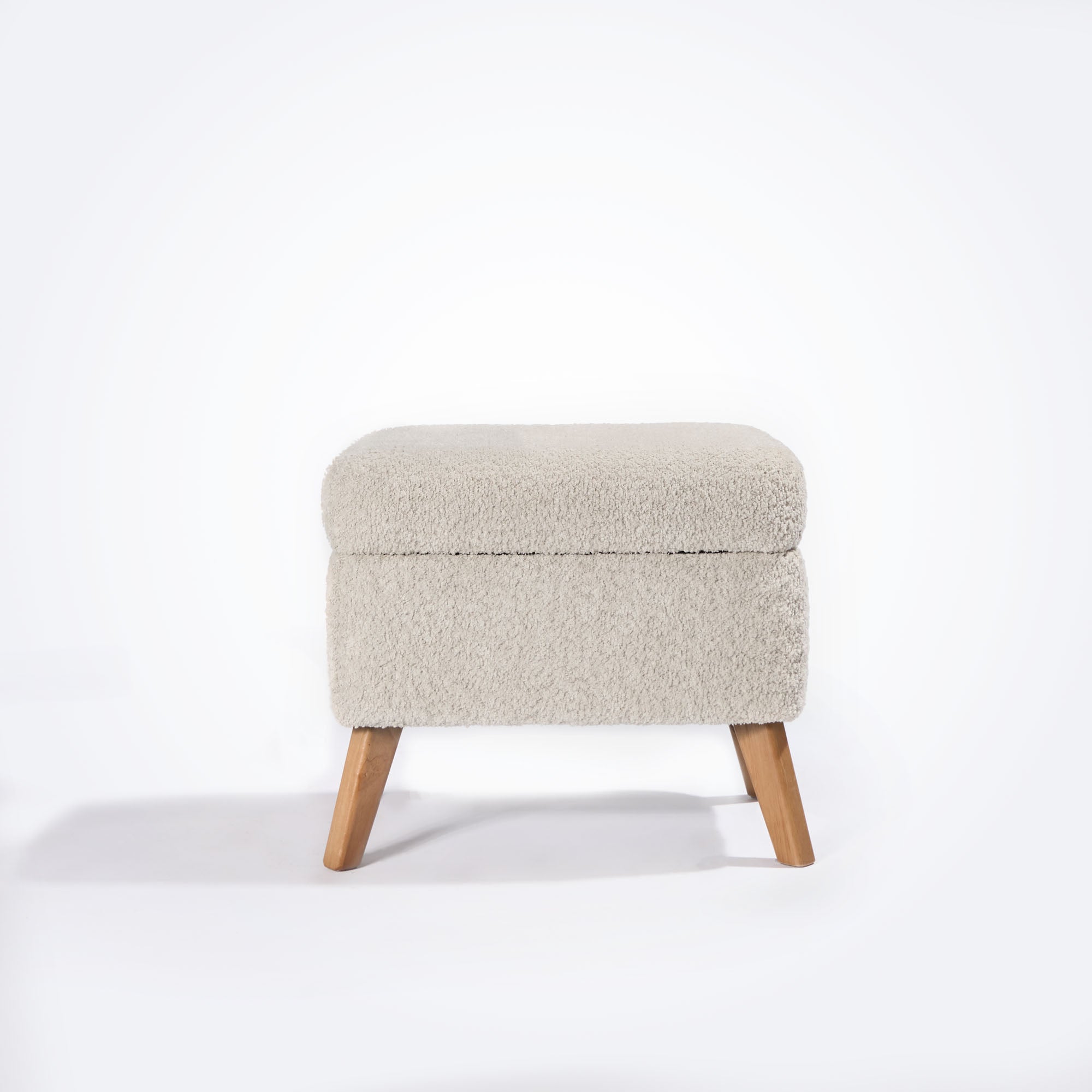 Front-facing cutout of the Oscar Luxe footstool in sage boucle showing gently rounded top, hidden storage, and angled oak-effect legs.