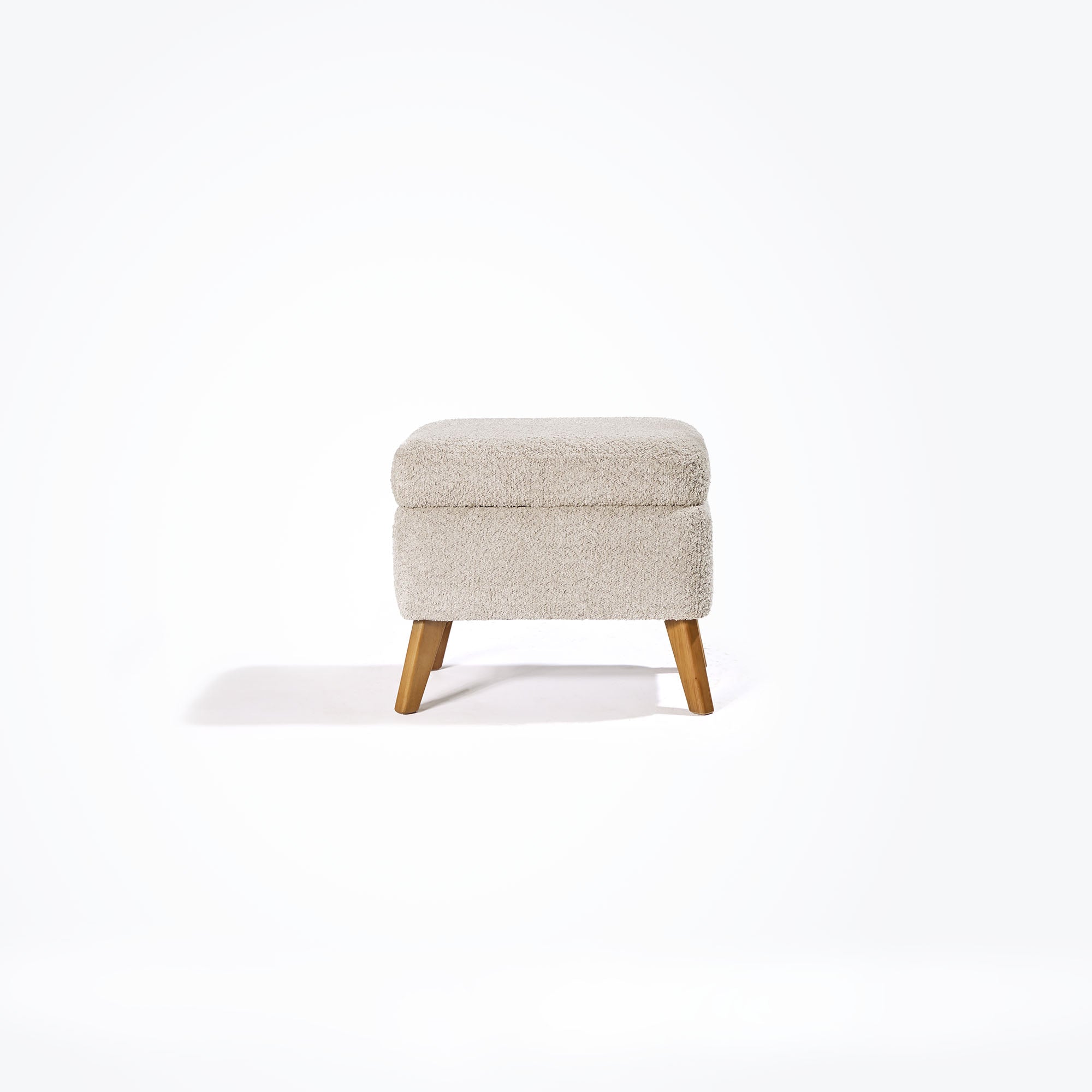 Front-facing cutout of the Oscar Luxe footstool in teddy mushroom with plush finish, gently rounded shape and tapered oak legs