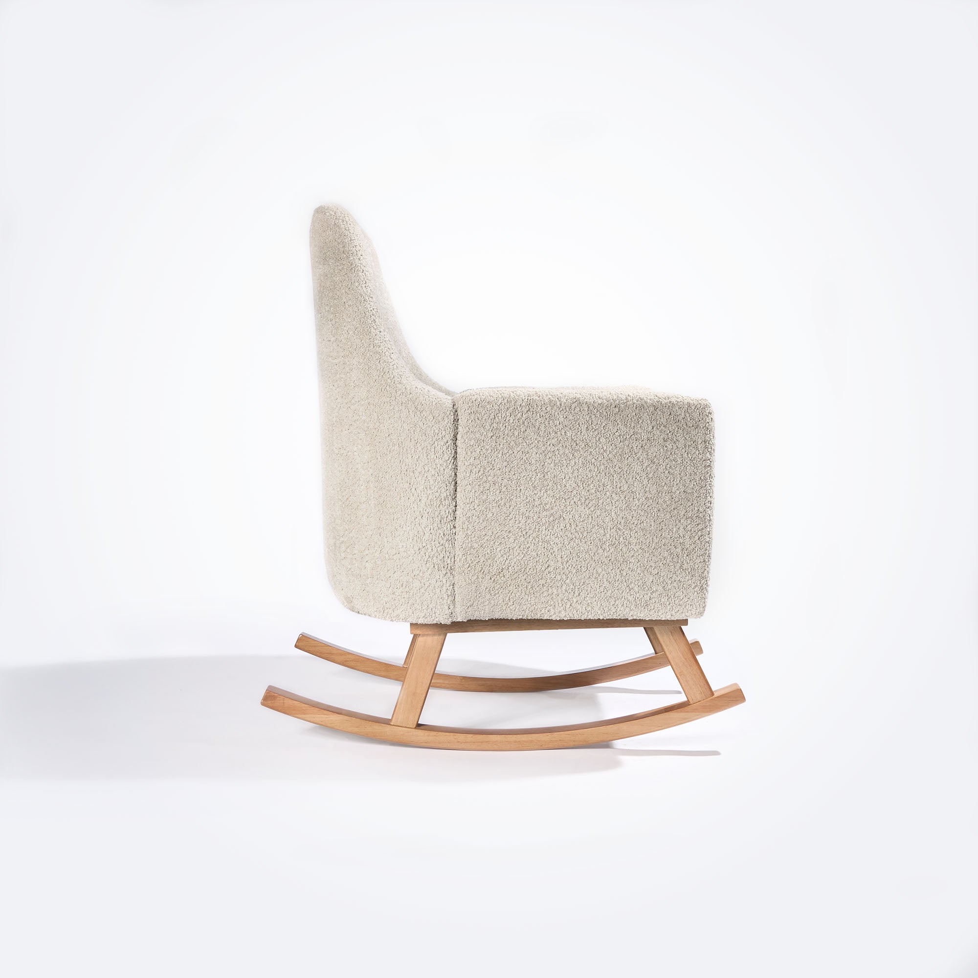 Side profile of the Oscar Luxe Rocking Chair in boucle sage, showing slim frame, smooth oak rocker and supportive armrest design