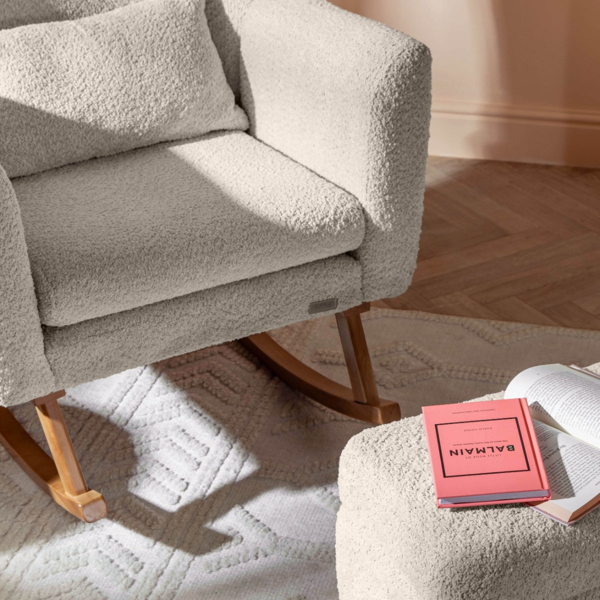 Lifestyle view of the Oscar Luxe chair and footstool in sage with books on top, showing plush comfort and calm nursery setup