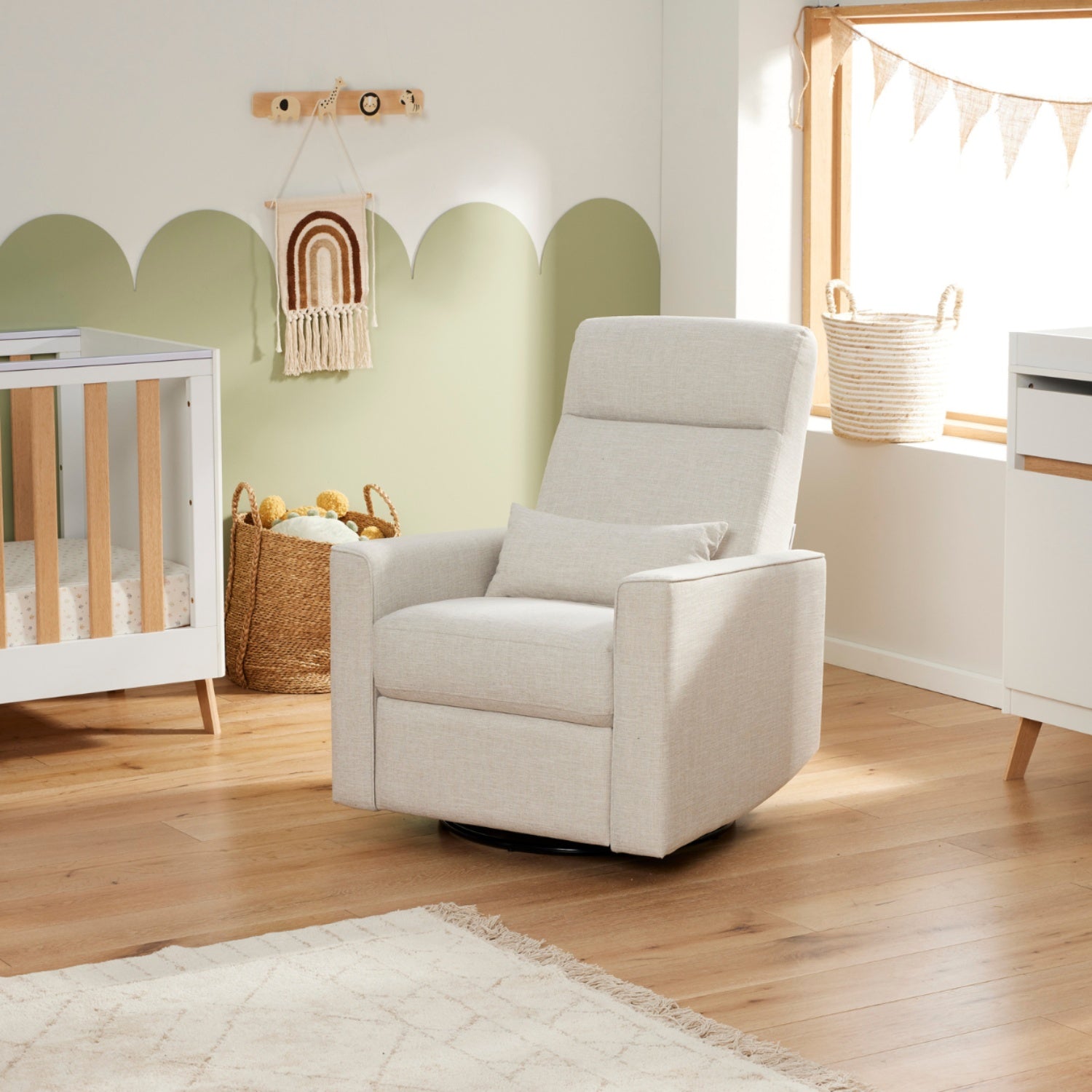 White glider recliner in a room with a crib and decorative elements