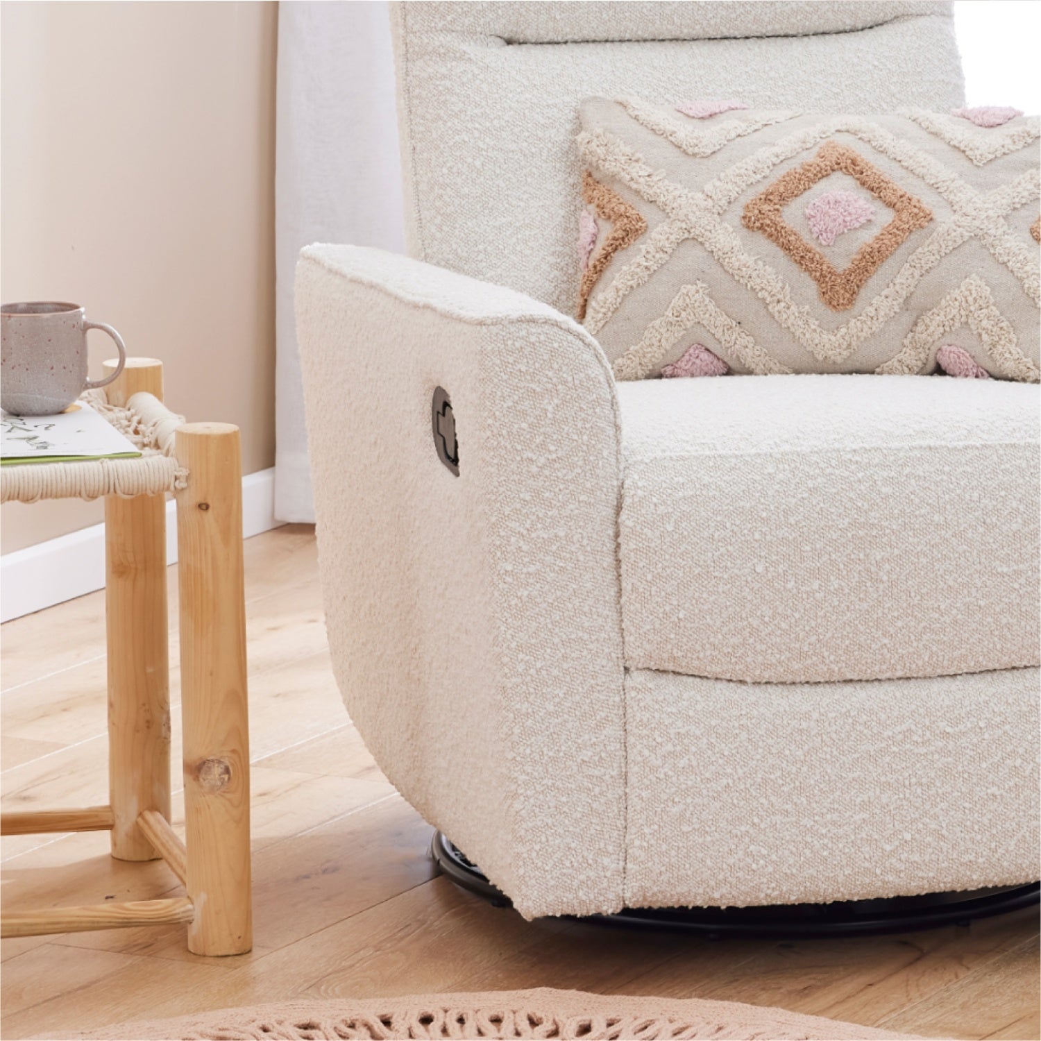 White textured recliner glider nursery chair with a patterned pillow next to a wooden side table.