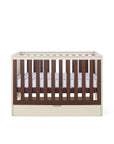 A Riley cot bed in cashmere and rich walnut, featuring a drawer beneath it in a white background.