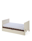 The Riley mIni cot bed in cashmere and rich walnut in toddler bed mode on a white background.