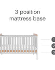 Rio cot bed in dove grey and oak displaying its adjustable 3-position mattress base for enhanced safety and ergonomic access during baby's growth stages.