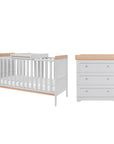 Rio nursery furniture set in dove grey and honey oak, featuring a cot bed with adjustable mattress base and a 3-drawer chest changer with a removable changing top for extended use.