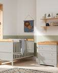 Nursery room setting featuring the Rio cot bed and chest changer in dove grey with honey oak details. The set combines modern simplicity with functionality, perfect for a stylish and practical baby room.