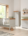 Nursery room view of the Rio three-piece room set in Honey Oak and Dove Grey, including a cot bed with top changer, a spacious wardrobe, and a chest changer for functional storage.