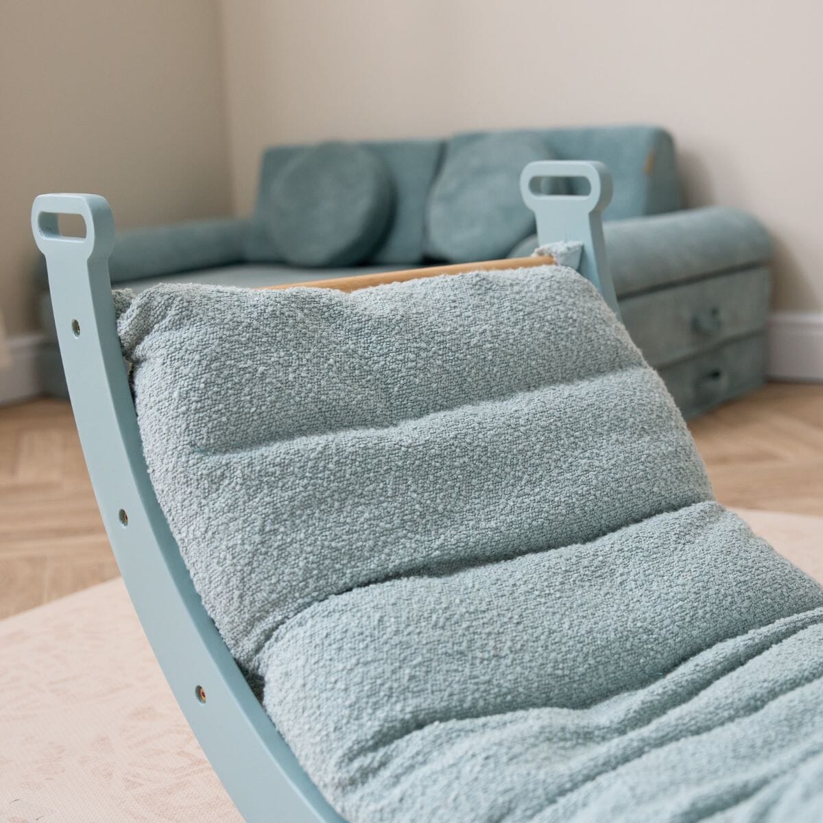 Side close-up of the Scala Pikler rocking frame with boucle ocean stone cushion, highlighting its thick texture and supportive padding.