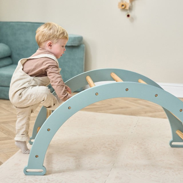 Boy playing on the Scala Arch in Blue. Play arch designed for climbing, balance, and imaginative play