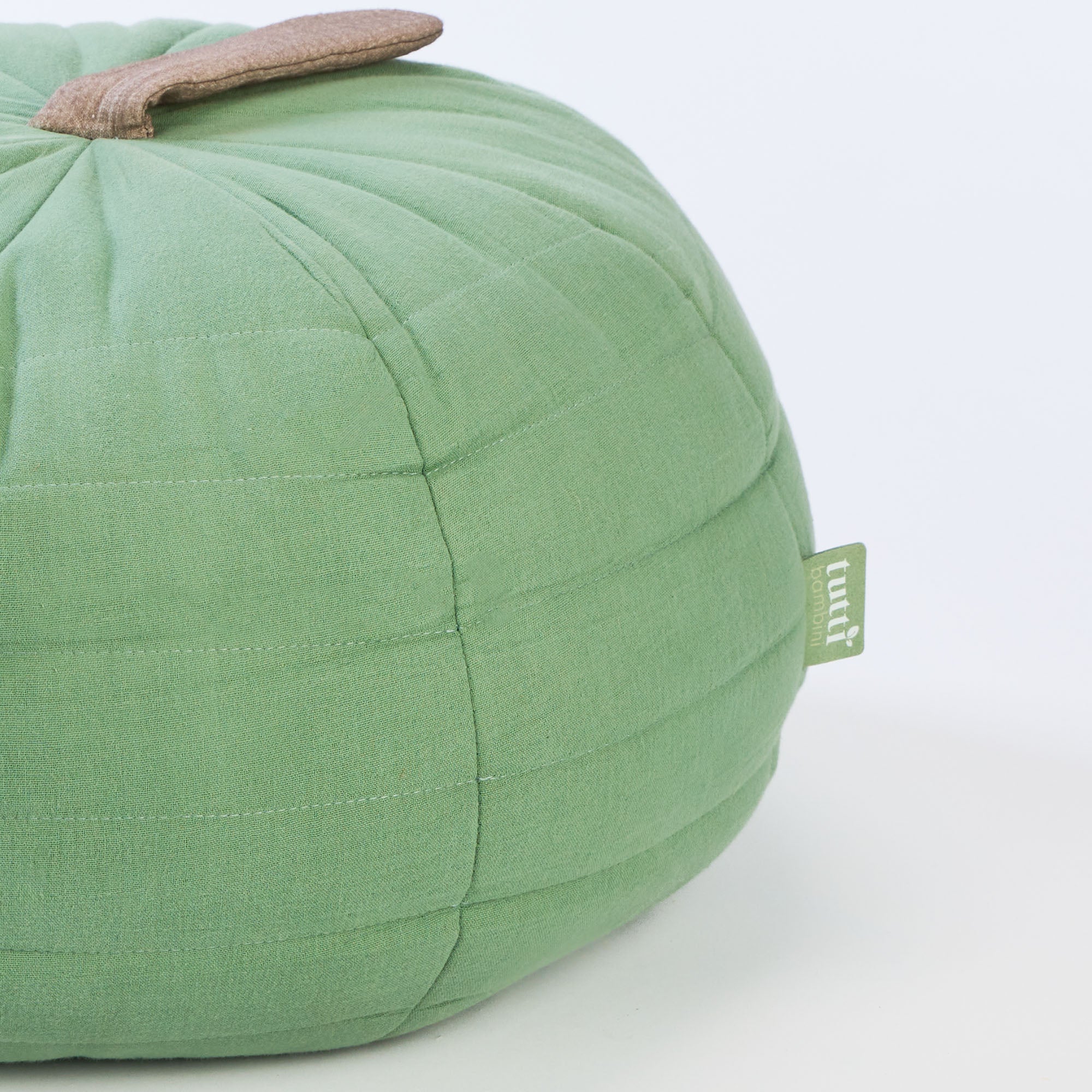 Side profile of the Soft Muslin Apple Cushion showcasing its rounded silhouette, stitched quilting and subtle neutral stem detail