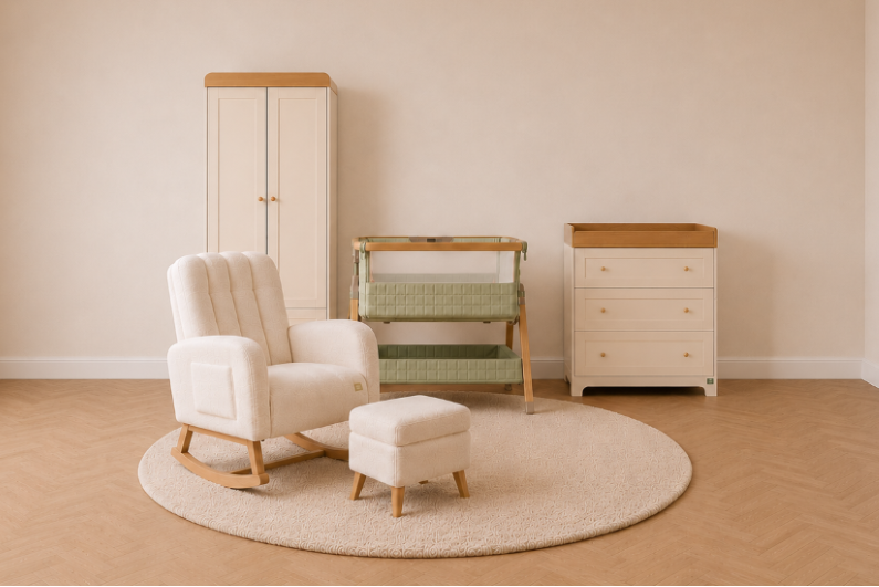 A styled nursery furniture set in a warm neutral room, featuring a cream-colored rocking chair and matching ottoman on a round beige rug, a cream wardrobe with a wood top, a green bedside crib and a matching cream dresser with a wood top.