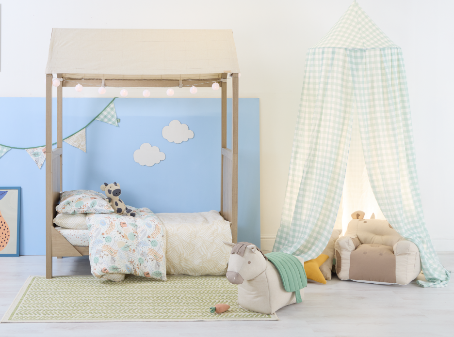 Children's bedroom with a toddler bed, canopy, and toys from the Good Life Collection against a blue wall.
