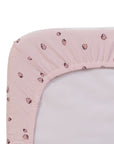 Close-up of the Tiny Tails pink crib sheet with a strawberry pattern on a white background