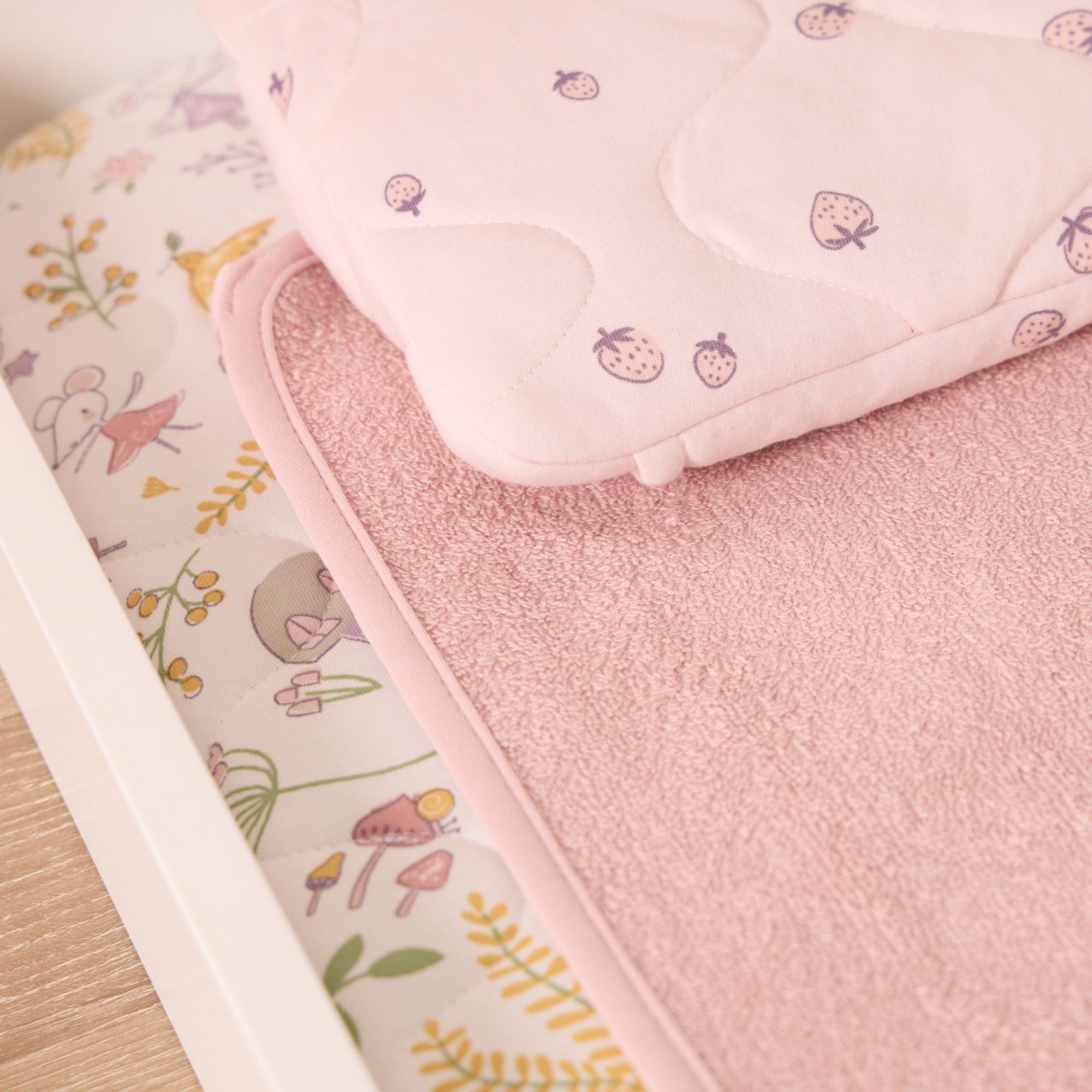 Close up of the Tiny Tales luxury changing mat, featuring a cushioned base, plush removable head pillow, and soft, absorbent towelling liner.
