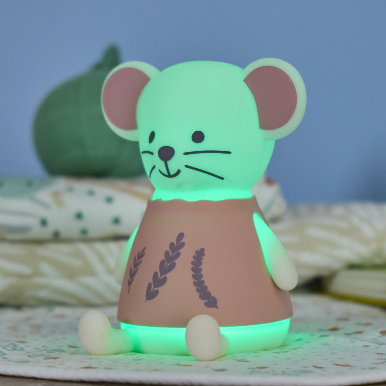 Margot Mouse glowing green mouse-shaped toy on a textured surface with a blurred background