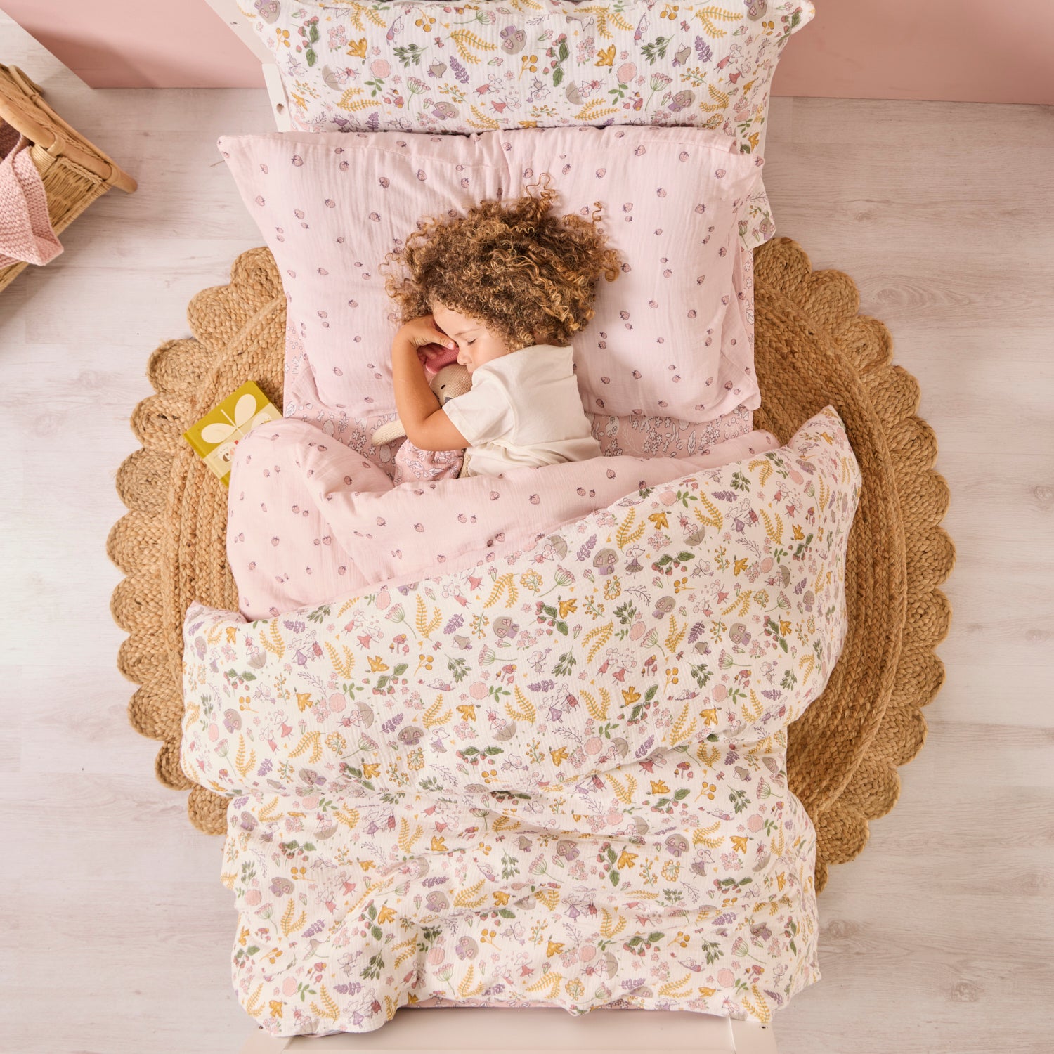 Child lying in a floral-patterned bed with matching pillows and comforter.