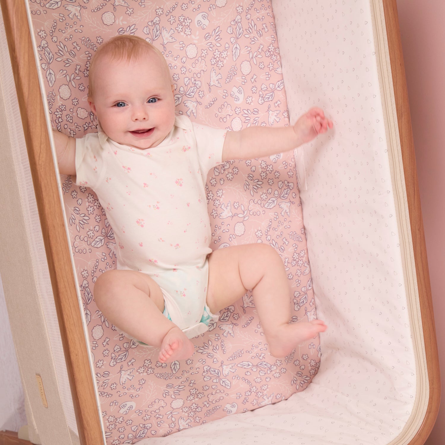 Baby lying on a floral-patterned mattress in a crib