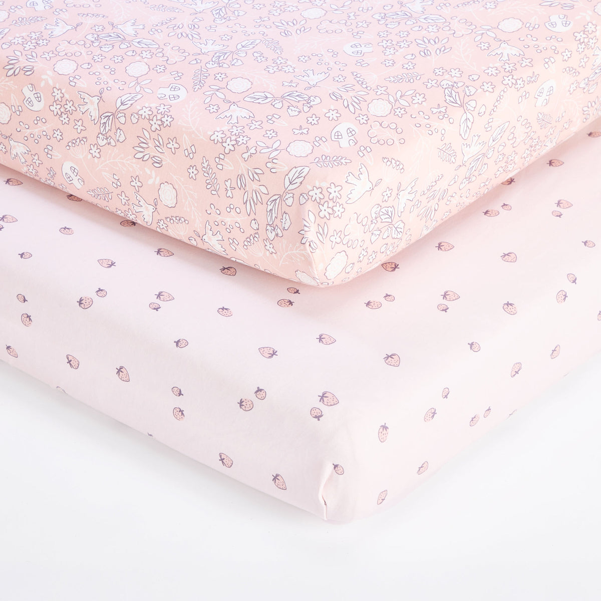Close-up of tiny tails cot bed fitted sheet layered over strawberry print sheet, showing elasticated corners and smooth fit.