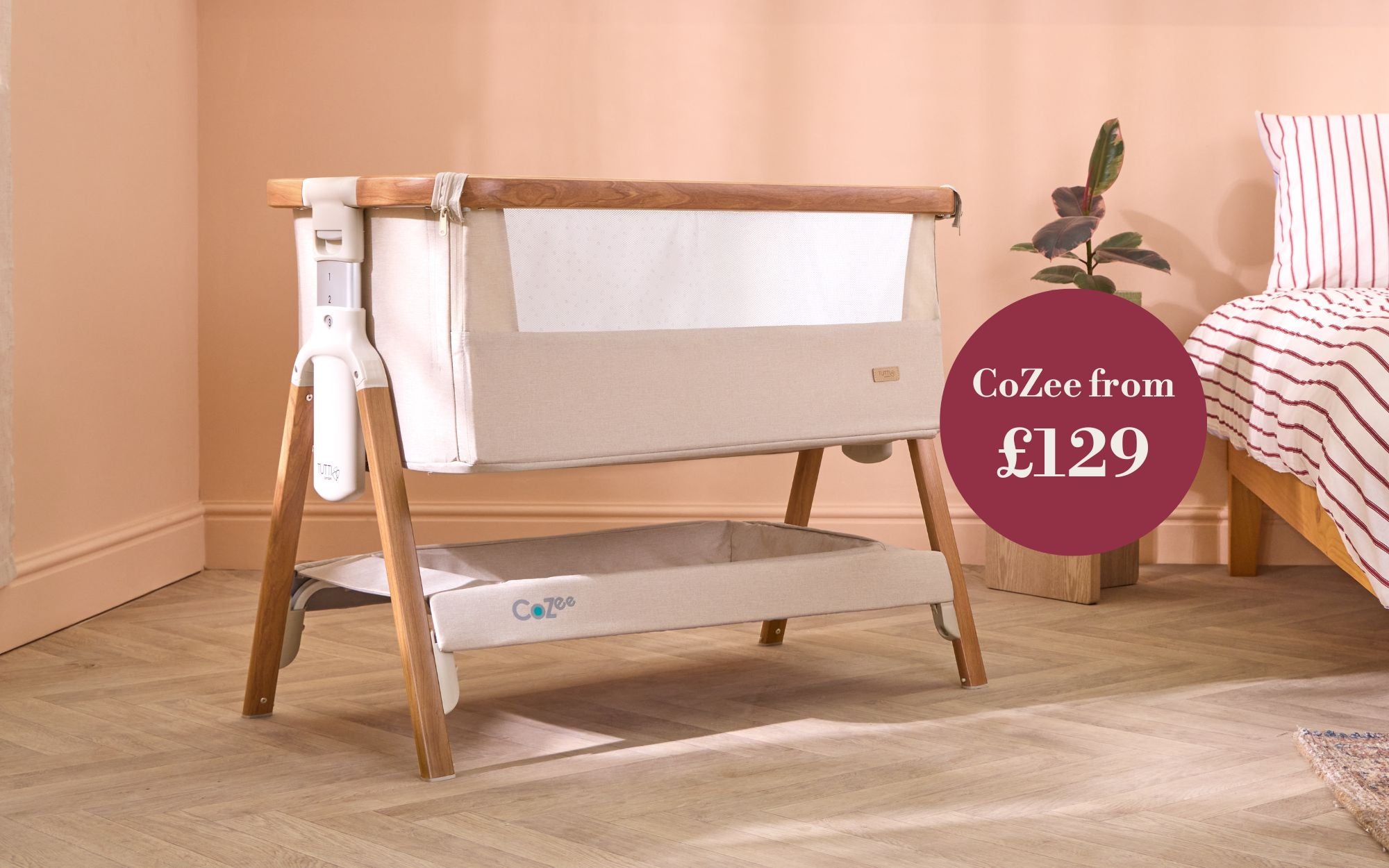 CoZee baby crib on a wooden floor with a pink wall in the background, with promotional text overlay.