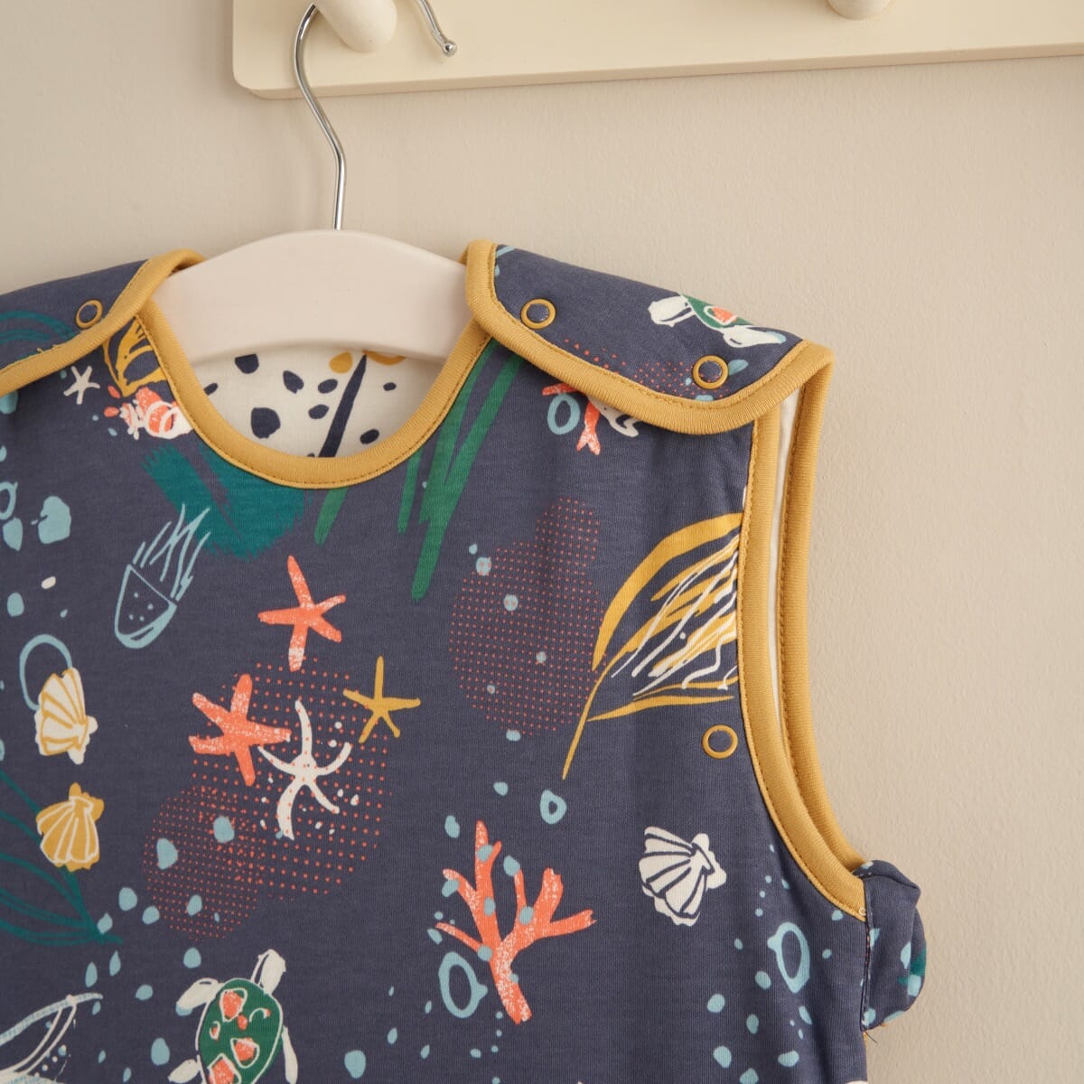 Our Planet baby sleep bag hung in a nursery setting, styled with playful décor to showcase size, print, and design in a real space