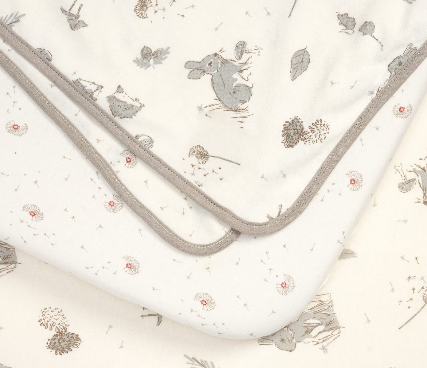 Close-up of the Cocoon bedside crib starter pack showing soft cotton fabrics with delicate woodland prints and smooth contrast edging