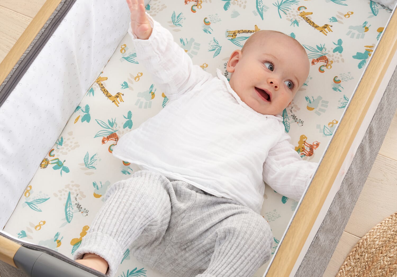 Baby lying on Run Wild fitted sheet with colourful safari characters, showing soft, breathable cotton for a comfy and playful sleep space