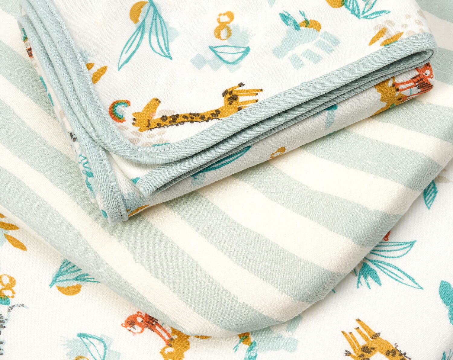 Close-up of Run Wild fitted sheets with safari animals and soft green stripes, highlighting smooth cotton fabric and gentle bound edges