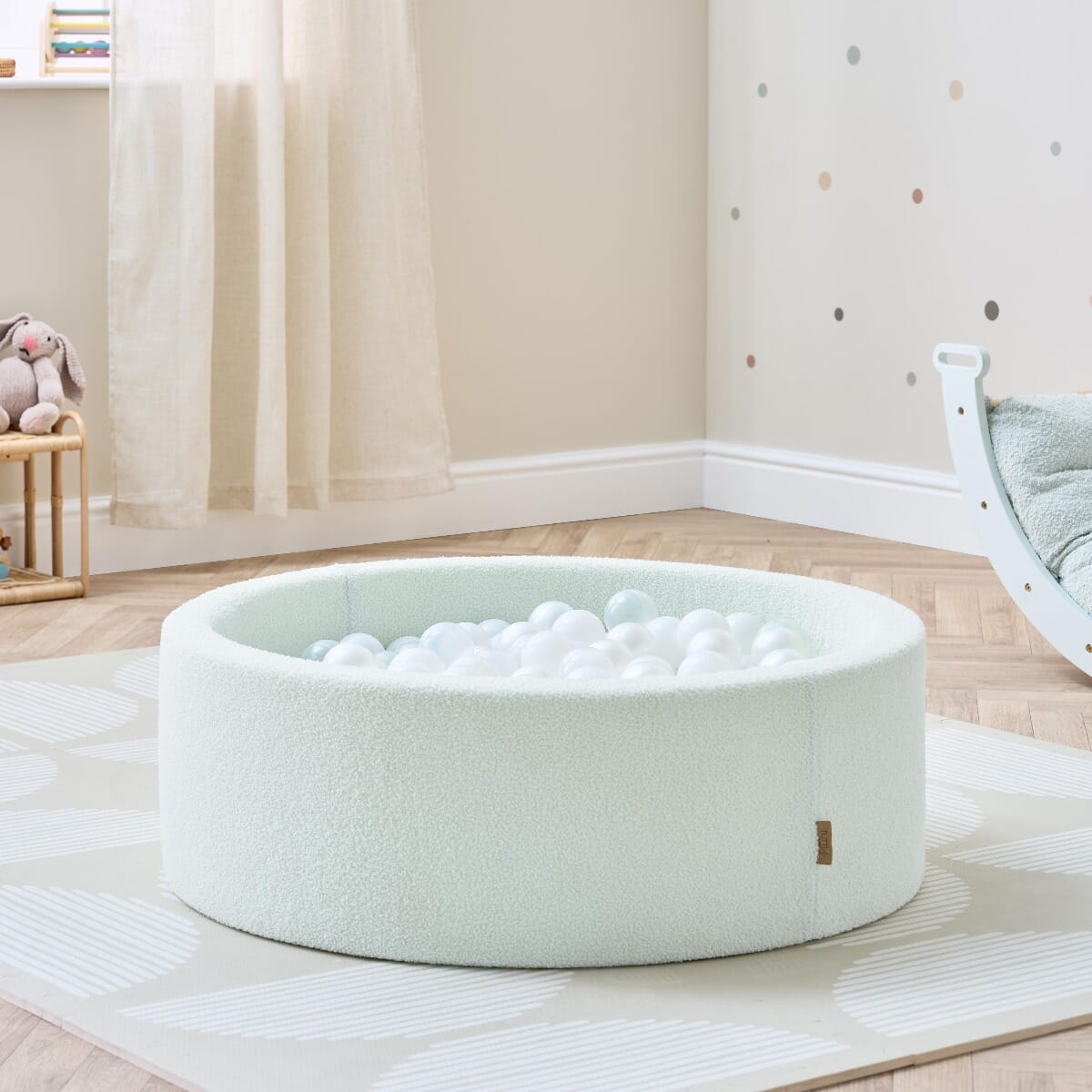 Bola baby ball pit in sea mist styled in a calm nursery setting, filled with soft white balls for sensory play and movement