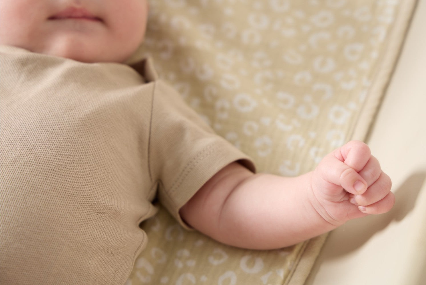 Close-up of baby’s arm and hand resting on the love cats changing mat liner, showing gentle cushioning and smooth cotton finish.
