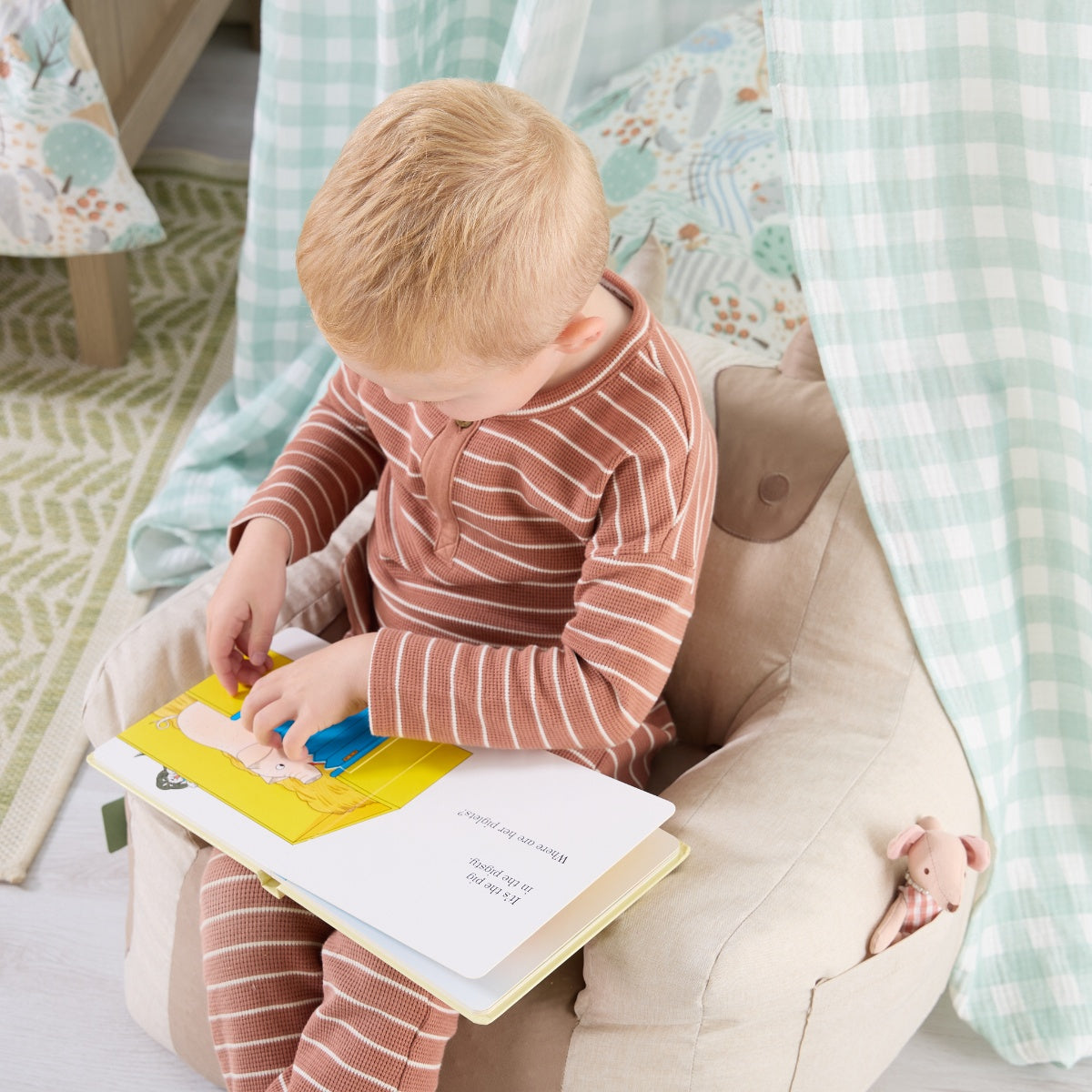 Toddler reading on the Clemi Cow beanbag chair in beige, highlighting supportive shape, cosy design, and soft fabric finish