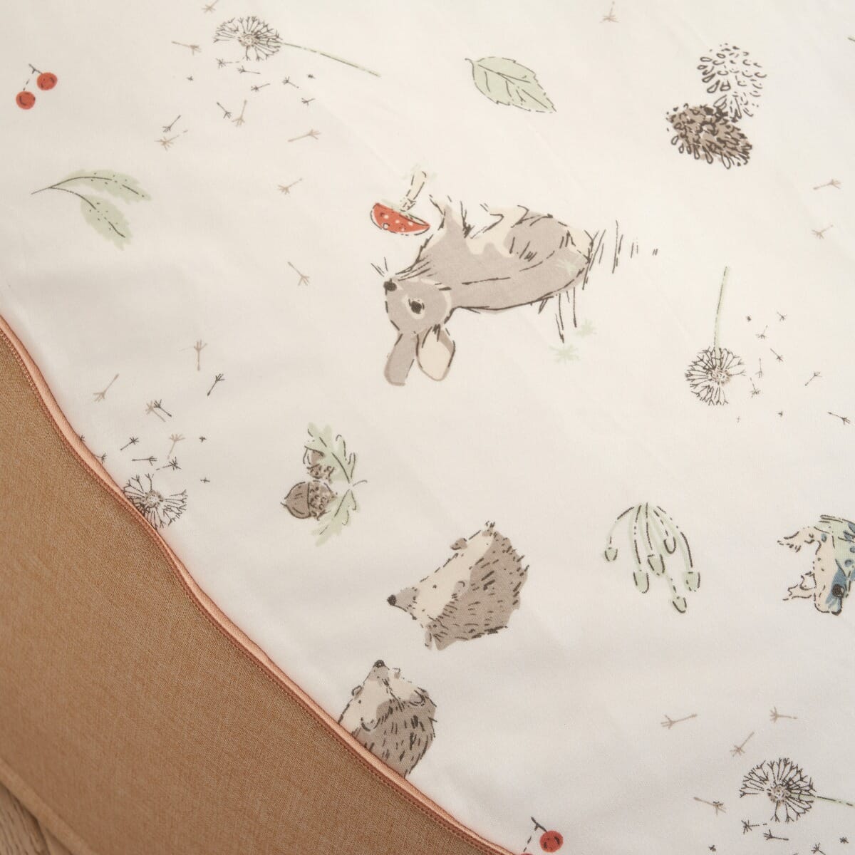 Fabric close-up of the Cocoon baby bean bag, showcasing the soft neutral upholstery and delicate woodland print top