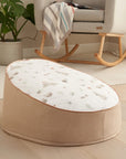 Cocoon baby bean bag shown in a calm nursery setting, featuring supportive padded sides and a soft, removable printed top