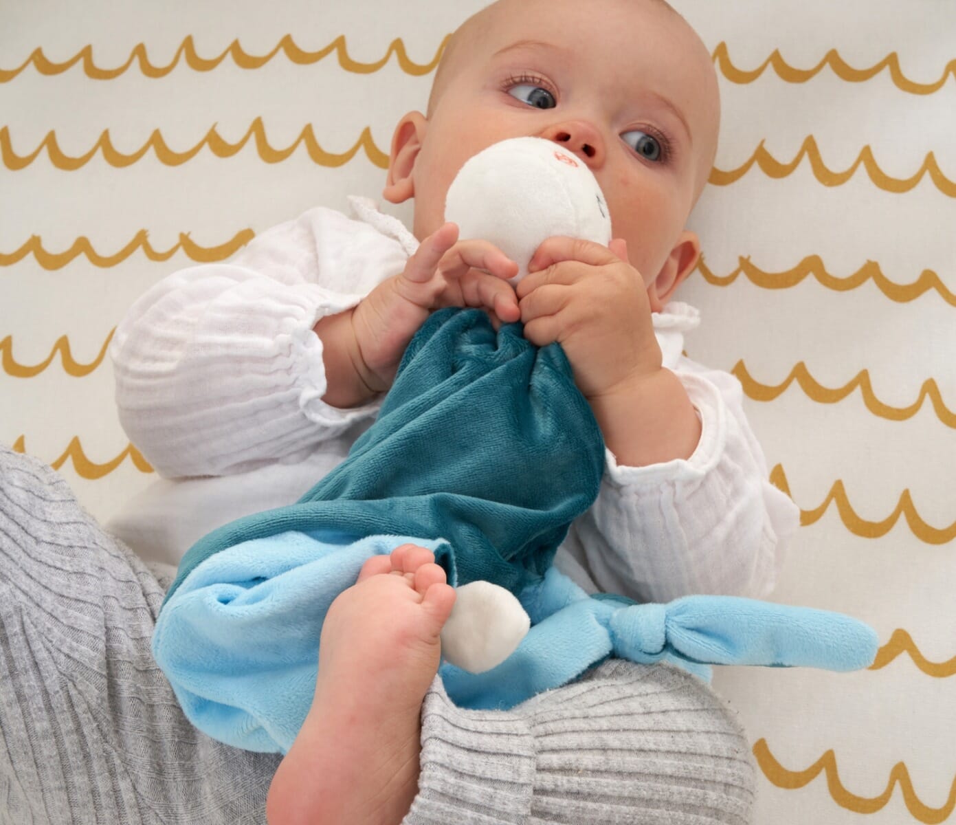 Baby cuddling the Our Planet comforter, showing its gentle plush fabric and easy-to-hold knotted corners for soothing comfort