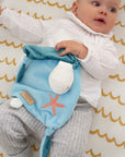 Baby relaxing with the Our Planet comforter, holding its plush head detail and soft fabric for tactile reassurance during play
