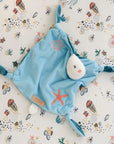 Overhead view of the Our Planet comforter on an ocean-themed sheet, highlighting its embroidered shell and starfish designs