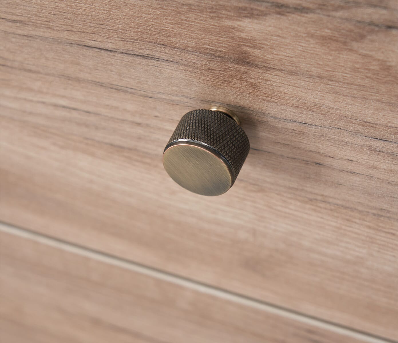 Close-up of the Como chest changer’s textured metallic knob in distressed oak, highlighting its smooth grip and refined modern detailing