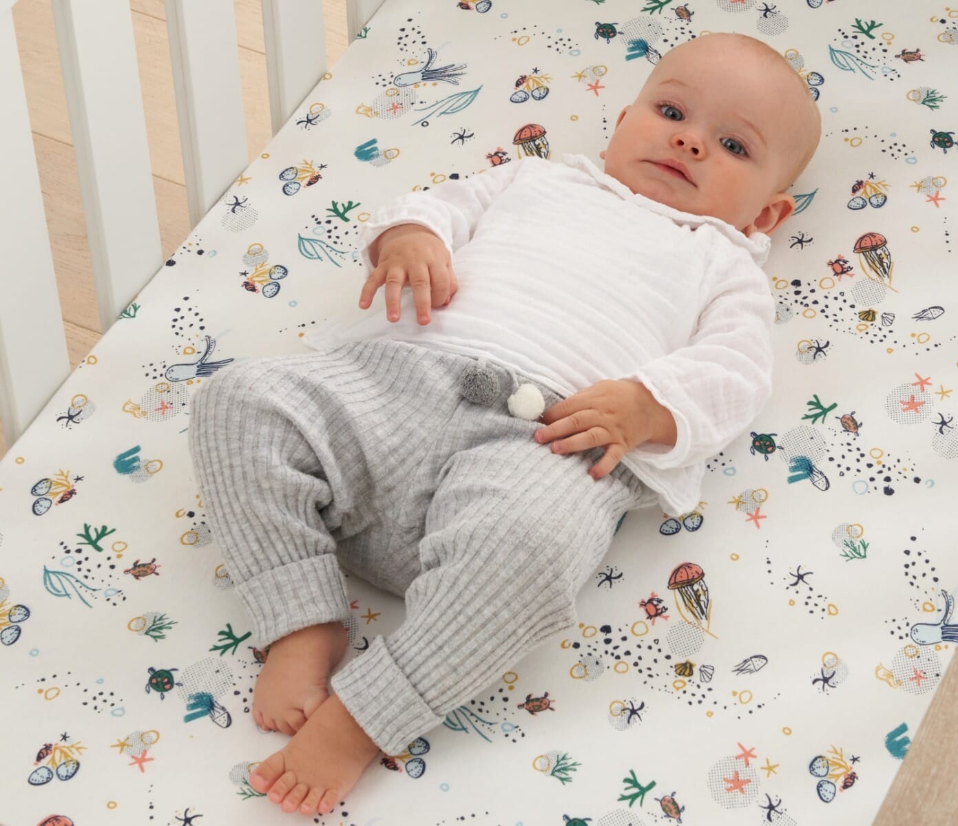 Feature image of baby lying on cot bed fitted sheet in Our Planet sea life print