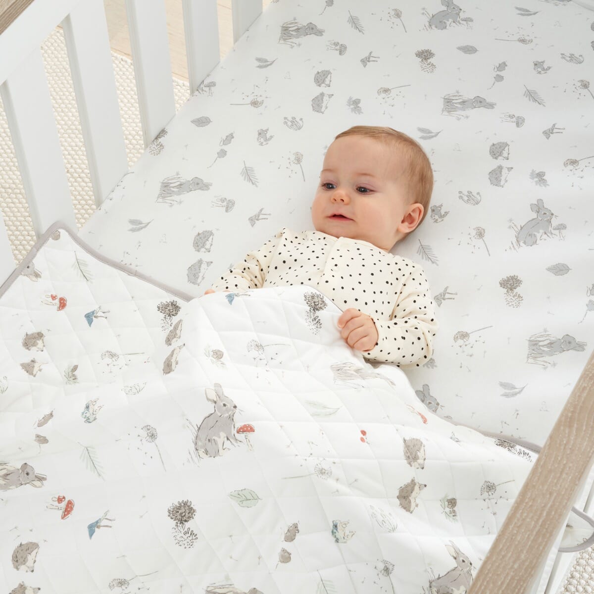 Baby tucked under Cocoon coverlet, quilted cotton with woodland animal prints providing warmth, comfort and a safe sleep layer