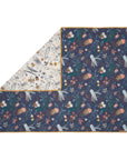Folded corner cutout of Our Planet coverlet, reversible quilted cotton with ocean designs and mustard trim for a versatile nursery look